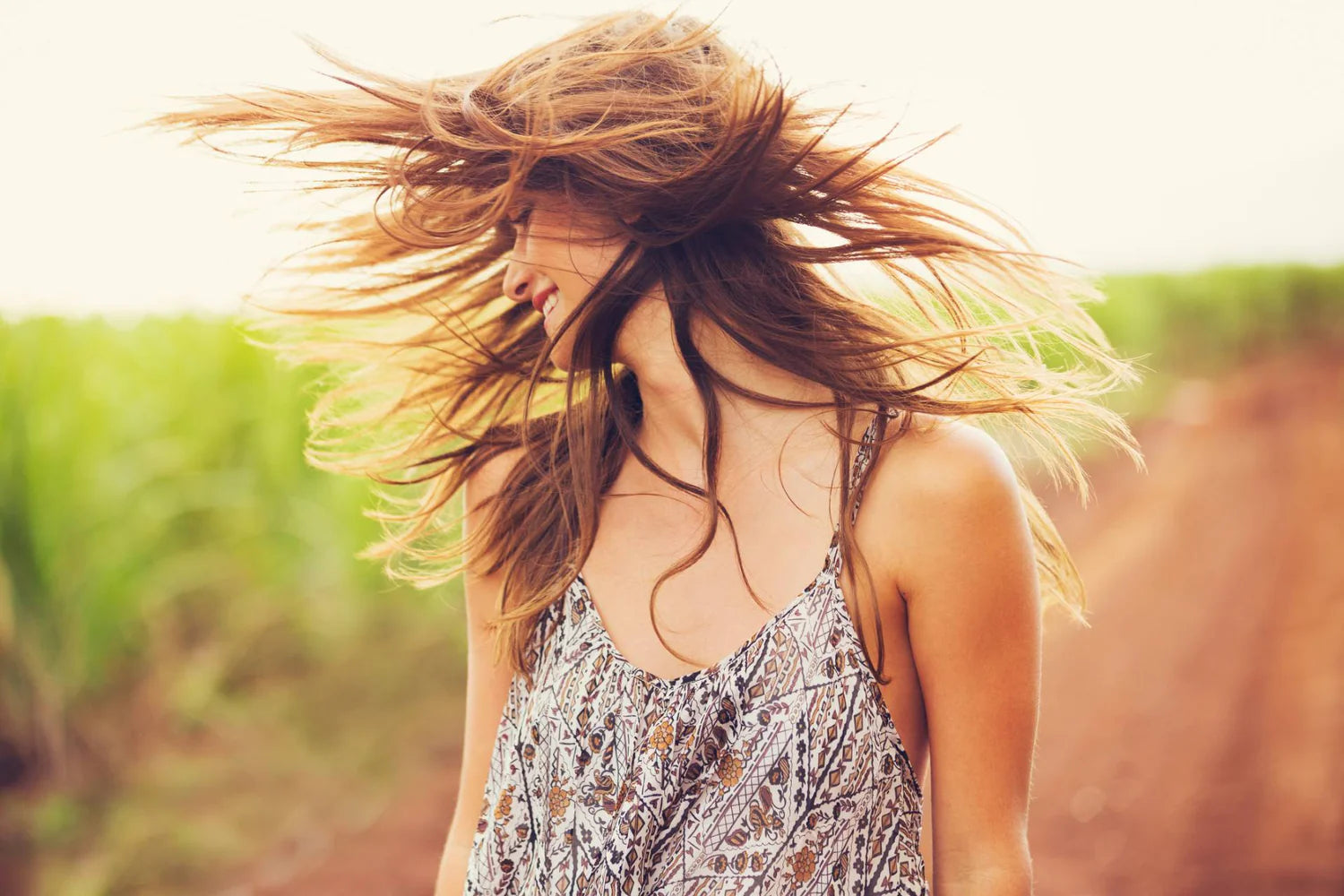 Woman with long hair blowing in the wind against a blurred natural background